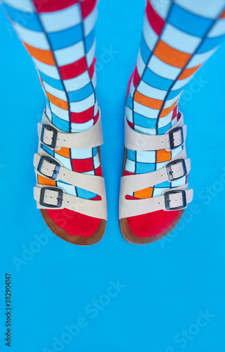 aerial view of the feet in sandals and colored socks on a blue background