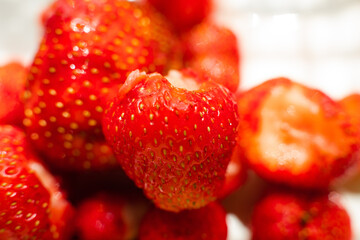 Wall Mural - Macro stock photo of large organic sweet strawberries in sunlight. Strawberry texture in close-up. Seeds and dirt.