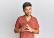 © Krakenimages.com - Young handsome man wearing casual summer clothes hands together and fingers crossed smiling relaxed and cheerful. success and optimistic