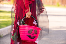 Hand Of Little Girl In Costume Of Halloween Witch Holding Pink Plastic Basket