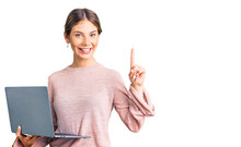 Beautiful Caucasian Woman With Blonde Hair Working Using Computer Laptop Surprised With An Idea Or Question Pointing Finger With Happy Face, Number One