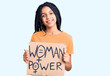 © Krakenimages.com - Cute african american girl holding woman power banner looking positive and happy standing and smiling with a confident smile showing teeth