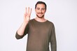 © Krakenimages.com - Young handsome man wearing casual clothes showing and pointing up with fingers number three while smiling confident and happy.