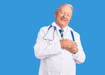 Senior handsome grey-haired man wearing doctor coat and stethoscope smiling with hands on chest with closed eyes and grateful gesture on face. health concept.