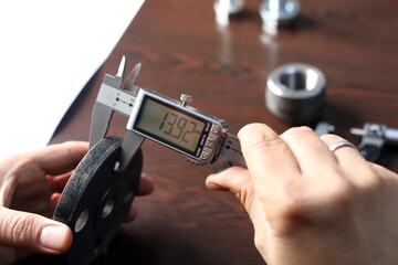 Wall Mural - The worker is measuring to thickness of flange with digital vernier caliper gauge. Vernier calipers are widely used in scientific laboratories and in manufacturing for quality control measurements.