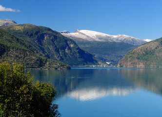 View From Urnes To The Lustrafjord And A Village On A Sunny Summer Day With A Clear Blue Sky And A Few Clouds