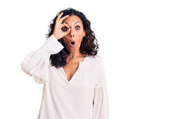 Canvas Print - Middle age beautiful woman wearing casual sweater doing ok gesture shocked with surprised face, eye looking through fingers. unbelieving expression.