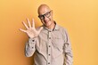 © Krakenimages.com - Middle age bald man wearing casual clothes and glasses showing and pointing up with fingers number five while smiling confident and happy.