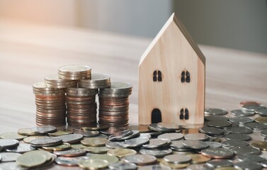 Stack of coins money with wood house model on table and sunlight, Business Growth concept, Financial risk. for plan saving finance and banking business concept.