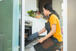 © Sirichai - Beautiful young asian woman preparing meat in oven in the domestic kitchen. Happy Asian Woman Roasting Chicken Meat In Kitchen Oven.