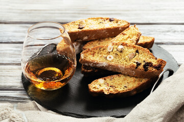 Italian biscotti cookies on black slate board and sweet wine Vin Santo. Fresh baked cookies with nuts