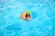© Volodymyr - Cute funny little toddler boy in a colorful swimming suit and sunglasses relaxing with toy ring floating in a pool having fun during summer vacation in a tropical resort. Panorama blue sea wave.