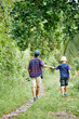 © DragonImages - Man with fishing rod holding hand of his little son when thay are walking on path in forest