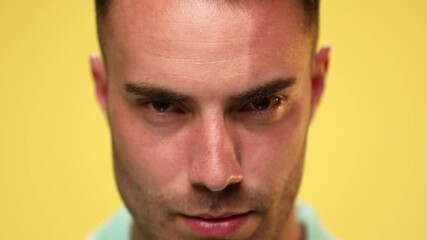 Poster - close up on an attractive casual guy looking deep into the camera with a tough look on his face on yellow background