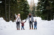 © Halfpoint - Father and mother with two small children in winter nature, walking in the snow.