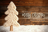Fototapeta Mapy - English Calligraphy Merry Christmas And A Happy New Year. White Fabric Christmas Tree With Snow. Brown Rustic Wooden Background
