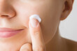 © fotoduets - Young woman finger applying white moisturizing cream on cheek. Care about clean and soft face skin. Daily beauty product. Closeup.