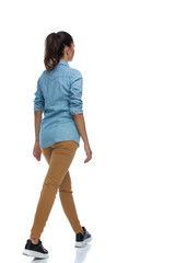 Wall Mural - side rear view of smart casual woman walking, wearing shirt