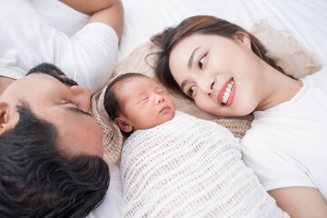 Wall Mural - smiling mother and father holding their newborn baby at home..portrait of happy family at home, young parents holding on hands little sweet newborn baby, love and happiness concept.