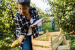 Young female african american farmer examining quality of pears after piking in orchard.