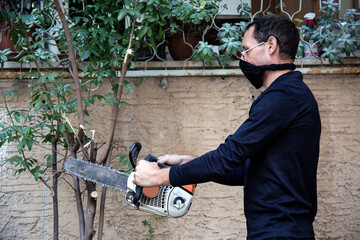 Close-up of woodcutter sawing chainsaw in motion, sawdust fly to sides. Man with the chainsaw. Dangerous job. Powerful chainsaw. Lumberjack hold chainsaw. Gardener lumberjack equipment.