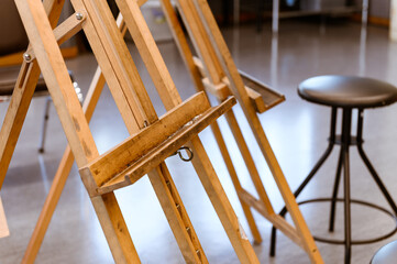 Close up of empty old stained wooden easel tripod for painting frame and canvas in the studio