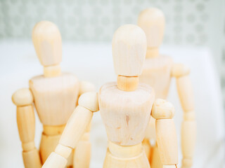 A figurine of a wooden man on hinges against the background of two other figures. Photo with focus in the foreground