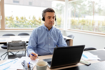 Poster - remote job, technology and business concept - middle-aged man with headset and laptop computer having conference call at home office