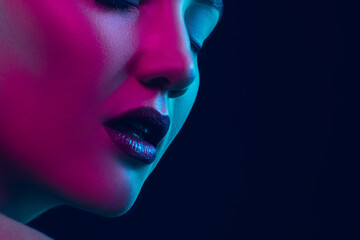 Inspiration. Portrait of female fashion model in neon light on dark studio background. Beautiful caucasian woman with trendy make-up and well-kept skin. Vivid style, beauty concept. Close up