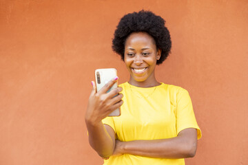 Canvas Print - Overexcited African-American female with afro hair using a modern smartphone checking social media