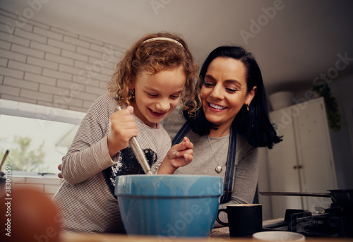 Cuadros en Lienzo Happy mother and daughter preparing batter and dough while mixing with a whisk i
