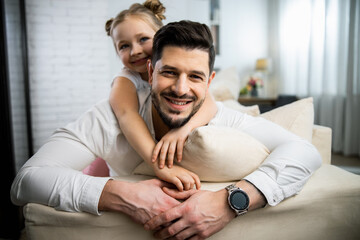 Wall Mural - Father and daughter lying and embracing at the sofa