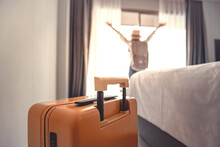 Close-up Luggage And Blurred Happy Tourist Woman Background In Hotel After Check-in. Conceptual Of Travel And Vacation.
