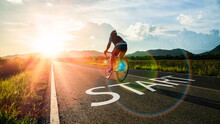 Concept Of Start Straight And Beginning For Cooperation.Blurry Man Ride On Bike And Word Start Written On The Road At Sunset Add Lens Flare.Concept Of Challenge Or Career Path,business Strategy.