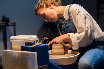 an experienced potter a girl in an art Studio makes a pot of clay with her hands