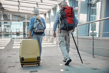 Wall Mural - Two senior tourists heading towards the airport entrance