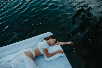 Wall Mural - Woman sleeps on a mattress floating in the water.