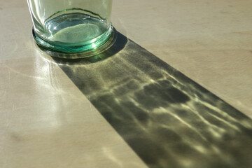 Wall Mural - Sunlight shining through a drinking glas showing caustic light effects.