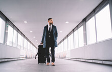 Pensive Man In Suit Walking Along Airport Hallway