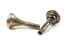 Two Vintage Trombone Mouthpieces Laying Down On A White Surface.  Close Up Of Brass Instrument Mouthpiece With Patina And Wear.  Musical Instrument Accessories Up Close.