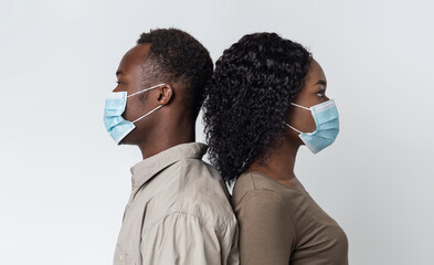 Black couple wearing protective face masks standing back to back