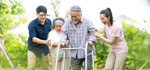 A family is trying to help Dad to walk because father is paralysed on lawn at home. paralysis and walking crutch concept.