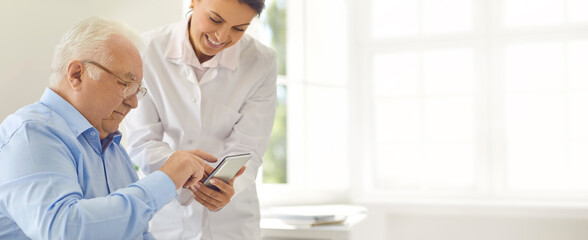 Friendly doctor teaching senior man to use special mobile app for tracking various health indicators
