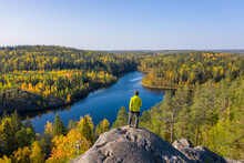 The Man On Top Of A Rock In The Autumn Forest On A Background Of A Beautiful Lake.