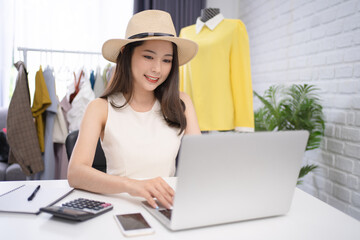 Women selling clothes online are smiling as they chat with their customers online on their computers.