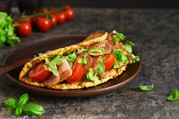 Wall Mural - Pancake, omelet with ham, salad and tomatoes on a concrete background.