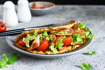 Wall Mural - Pancake with ham, salad and tomatoes on a concrete gray background. Breakfast on the kitchen table.