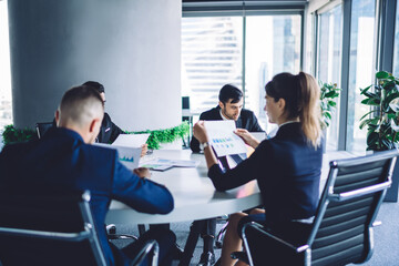 Prosperous team of partners 30s have brainstorming meeting for consultancy about business plan, successful male an female proud ceo discussing information from paper documents talking indoors