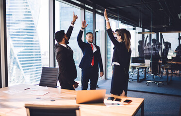 Wall Mural - Accomplished male and female entrepreneurs collaborating togetherness on business idea brainstorming in modern office interior,happy crew in formal clothing giving five satisfied with approved project