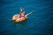 Carefree Young Girl Woman Enjoying A Relaxing Day At Sea, Floating On An Inflatable Ring, Top View. Sea Vacation Concept